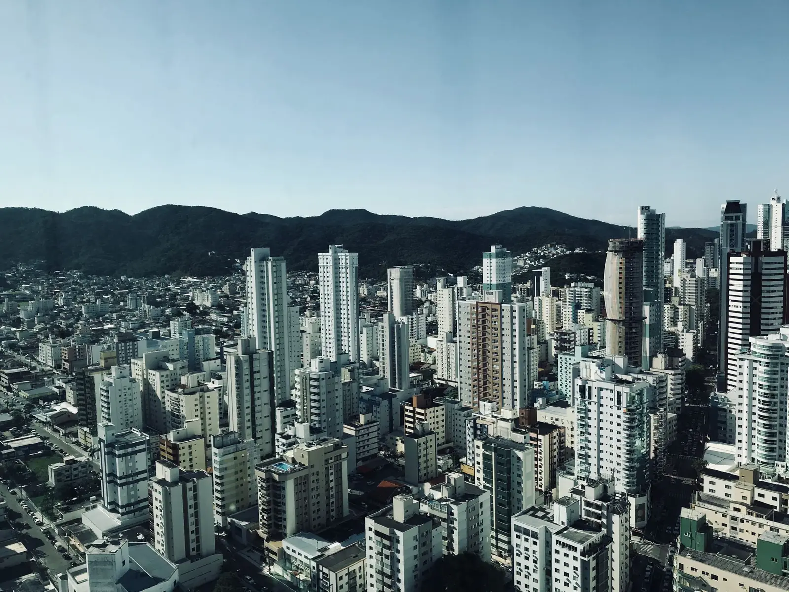 Vista aérea dos prédios de Balneário Camboriú com morros ao fundo