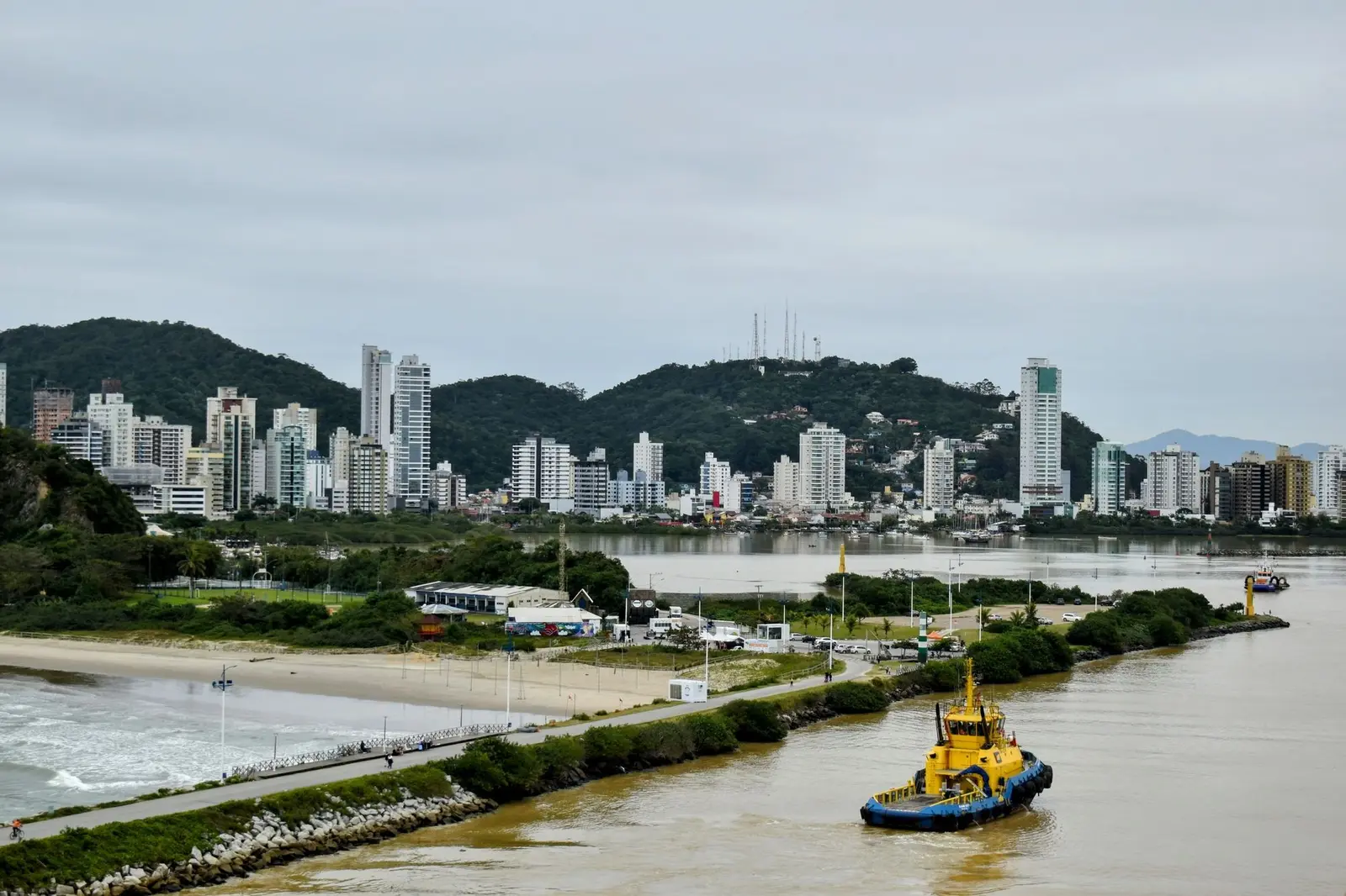 Foz do rio Itajaí-Açu com prédios da orla e rebocador no canal